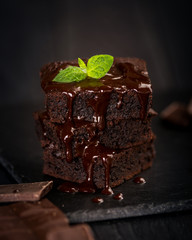 A stack of chocolate brownies on wooden background with mint leaf on top, homemade bakery and dessert