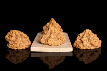 Group of five whole homemade brown coconut biscuit with chocolate on small wooden cutting board isolated on black glass