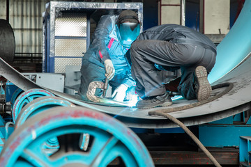 Two workers while doing a welding with arc welder