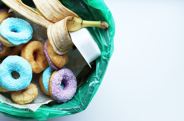 colorful donuts, the peel from the ban are in the trash, an urn with food waste