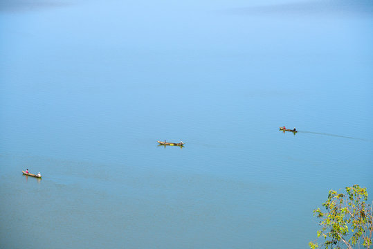 fishers with three canoes fishing and rowing in the middle of a calm lake