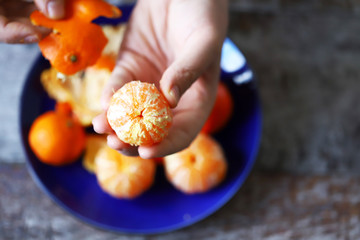 Men's hands are peeling mandarin. Tangerines in a plate. Mandarin peel.