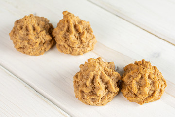 Group of four whole homemade brown coconut biscuit with chocolate on white wood