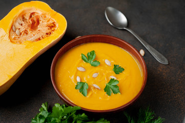 pumpkin cream soup with seeds and herbs on a stone background. healthy food.