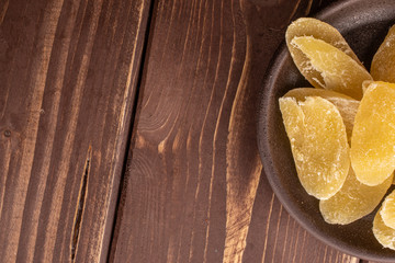 Lot of slices of dried yellow pineapple with brown ceramic coaster flatlay on brown wood