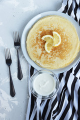 pancakes for Shrovetide on a striped background with forks and sour cream. seeing off winter. spring treats
