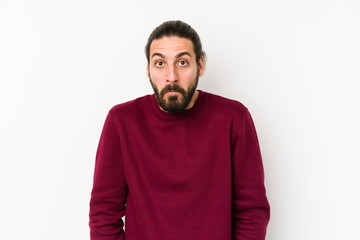 Young long hair man isolated on a white background shrugs shoulders and open eyes confused.
