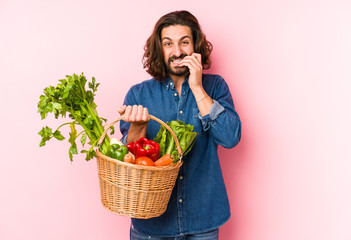 Young man picking organic vegetables from his garden isolated biting fingernails, nervous and very anxious.