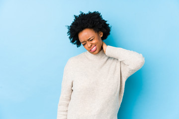 Middle aged african american woman against a blue background isolated suffering neck pain due to sedentary lifestyle.