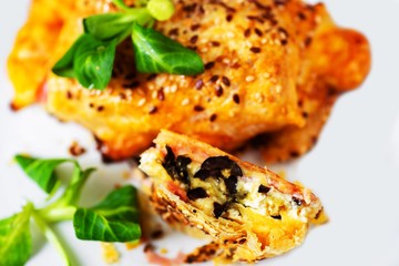 Puff pastry with cheese, ham and olives, sprinkled with sesame seeds.