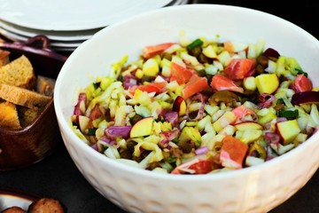 Chicory, apples, oranges, onion and capers salad in bowl, croutons and plates.
