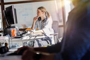 Young female programmer sitting at the desk in her office and working .