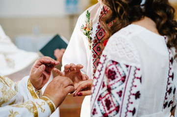 Obraz premium The priest blesses hands with the wedding rings of the bride and groom in the church.