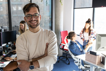 Portrait of senior programmer and group leader.he standing at the office in front of his workers. - obrazy, fototapety, plakaty