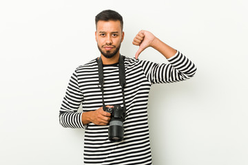 Young south-asian photographer showing a dislike gesture, thumbs down. Disagreement concept.