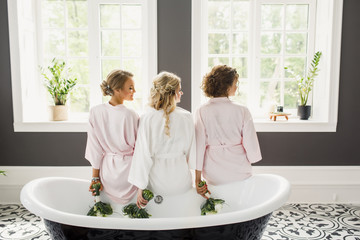 young beautiful blonde wedding bride in a beautiful white dress having fun with bridesmaids in the...