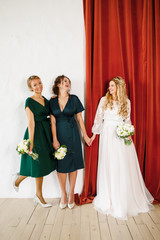 young beautiful blonde wedding bride in a beautiful white dress stands on a red background
