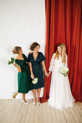 young beautiful blonde wedding bride in a beautiful white dress stands on a red background