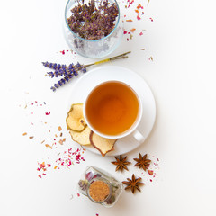 herbal tea in white cup with ingredients on white background