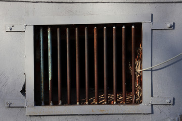 A metal grid in the wall of a building. Basement lattice in the wall of the house. Uneven metal...