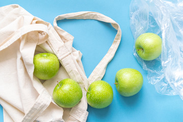 Eco friendly friend's bag for linen products with beautiful green apples on a blue background against a plastic bag.