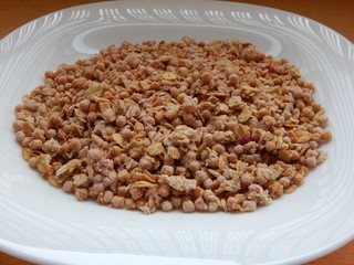 Dry muesli on a white plate close up.