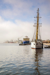 The embankment of the Neva with an icebreaker, a sailboat on a foggy spring warm day in April