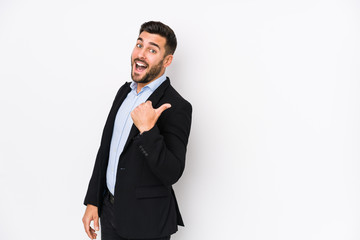 Young caucasian business man against a white background isolated points with thumb finger away, laughing and carefree.
