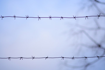 Barbed wire against blue clear sky