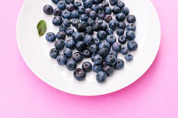 Blueberry berries close-up. Fresh blueberries on a soft pink background in plate.