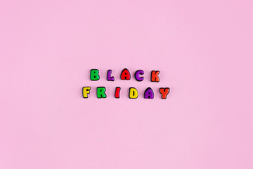 Inscription Black Friday composed of colored letters on a pink background. Discount and advertisement. Seasonal sale in stores. The photo for a banner or poster on the site and on social networks.