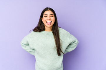 Fototapeta premium Young indian woman isolated on purple background funny and friendly sticking out tongue.