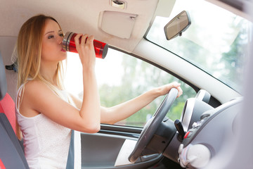 woman drinking coffee while driving her car
