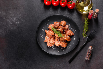 Chicken fillet in sesame seeds, teriyaki sauce on a black stone plate