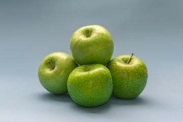 A bunch of beautiful green apples on an isolated blue background. Top view with copy space