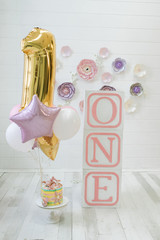 Decor of the girl's first birthday. Cubes labeled one. Holiday gel balloons