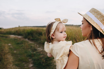 Family, mom, daughter are walking on a hill in the field in yellow identical dresses.