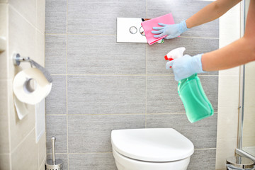 A woman in gloves cleans the bathroom.