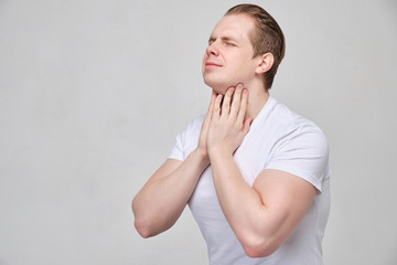 A man massages his neck in pain. Thyroid problems concept.