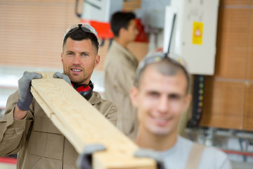 two men carrying length of wood