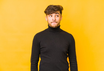 Young arabian man isolated on a yellow background confused, feels doubtful and unsure.