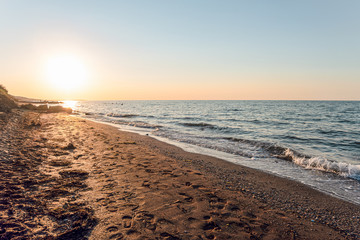 Empty sandy beach with footprints. Evening sea landscape with low sun on horizon. Peresyp resort...