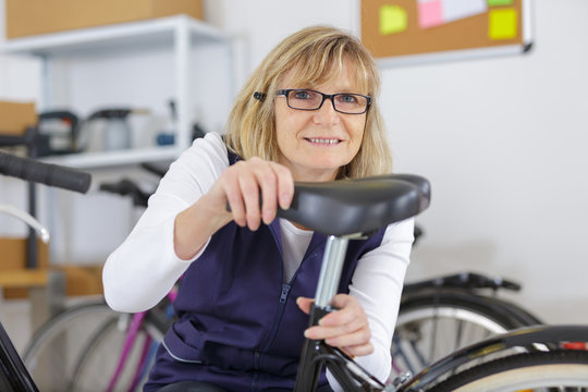 mature woman working in a biking repair shop - Powered by Adobe