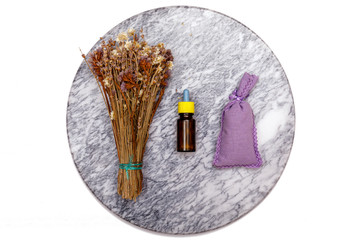 Essential oil and lavender flowers. Selection of essential oil on marble tabel with various organic herbs and flowers in the background.