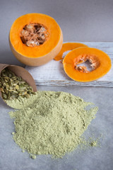 Pumpkin flour is scattered on white paper near a ripe orange pumpkin. An alternative to pumpkin flour.