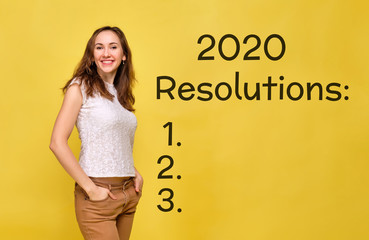 A girl in summer clothes stands on a yellow background and smiles with resolutions and a list for 2020.