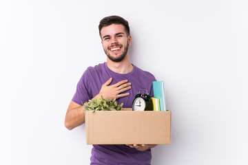 Young caucasian man moving a new home isolated laughs out loudly keeping hand on chest.