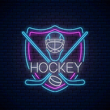 Hockey Championship Neon Sign With Hockey Sticks, Puck And Goalkeeper Helmet In Shield Frame. Ice Hockey Competition Logo, Emblem, Symbol Design. Vector Illustration.