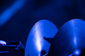 A pair of crash cymbals in a rack waiting to be played by an orchestra musician on stage of blue...