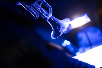 A trumpet player playing the trumpet in a big band concert on stage with blue stage lights